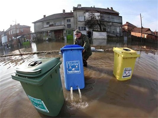 Мъж от Елхово мести контейнер за боклук, от който изтича вода. 
СНИМКИ: РОЙТЕРС И БУЛФОТО