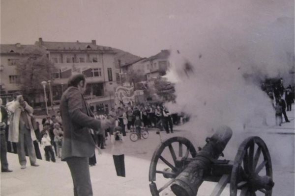 Стоян Шиеков гръмва с черешов топ в Перущица през 1976 г., Михаил Кръстев (вляво) снима с камера. Отсреща е официалната трибуна, където Борис Велчев и Дража Вълчева от Политбюро са обстреляни с кълбо дим и сажди от стар брой на в. "Антени".
