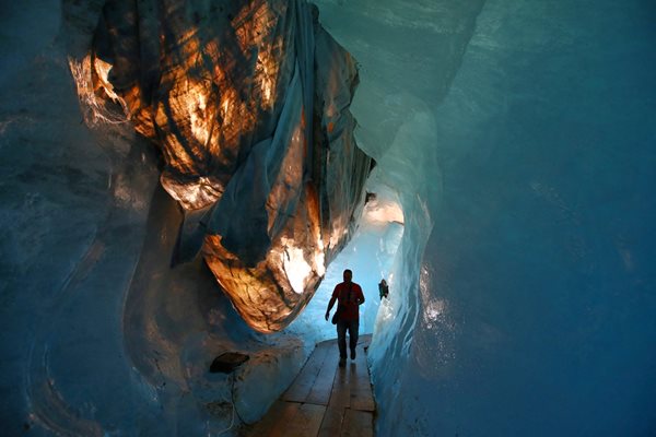 Стотици хора годишно се разхождат в Ледената пещера, покрита с материал, който да предотвратява топене, в ледника Рона в Швейцарските Алпи.

