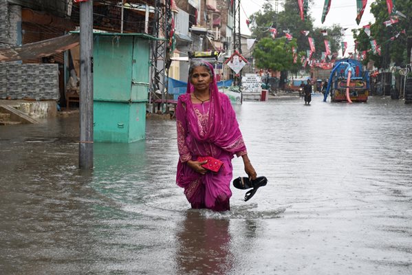Момиче върви по наводнена улица в Хидерабад, Пакистан.