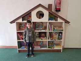 До библиотеката в детската градина към Италианския лицей. Къщичката е проектирана и направена собственоръчно от майка му и баща му.