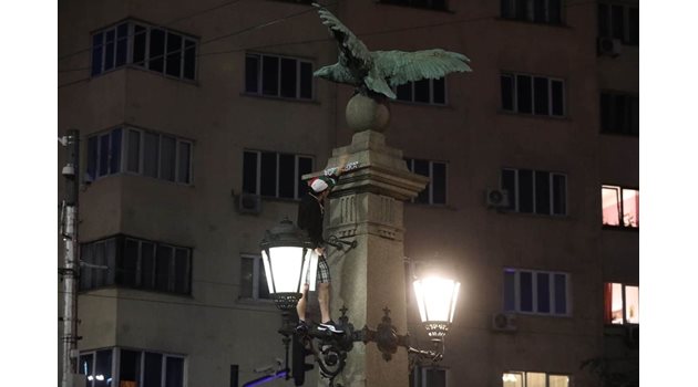 Момче от протестиращите се качи на една от статуите на орлите, за да залепи стикер с надпис: "Оставка!" СНИМКА: Николай Литов