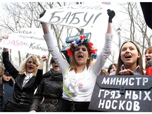 Активистки на феминистката организация “Фемен” протестират в Киев срещу липсата на жени министри в новия кабинет. Плакатът долу вдясно гласи: “Министър на мръсните чорапи.”