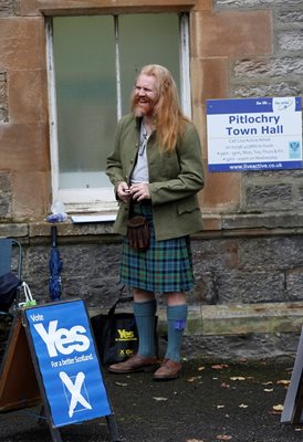 Поддръжник на независимостта, облечен в традиционна шотландска поличка, посреща избиратели пред една от секциите.