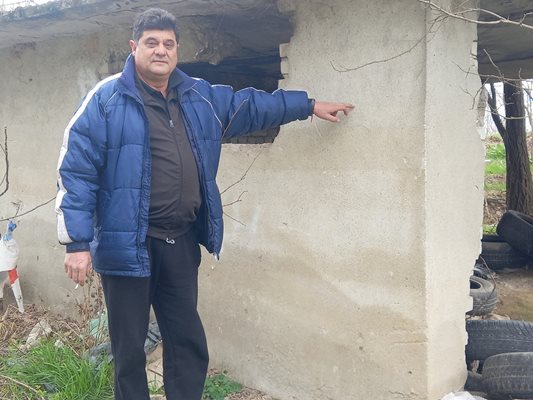 Фермерът Желязко Атанасов показва на стената на стар заслон докъде се е покачило нивото на водата при последното наводнение.