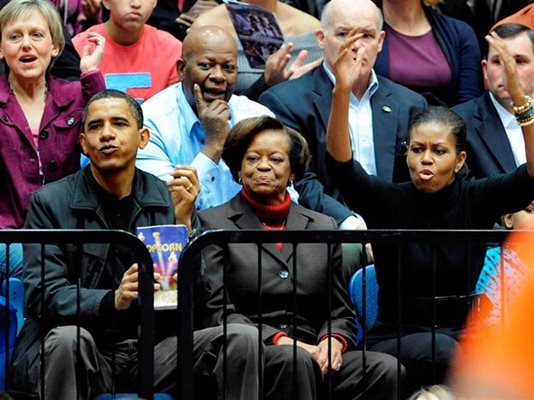 Обама гледа баскетболен мач заедно с Мишел и тъщата Мариян. Играят отборите на университетите “Джордж Вашингтон” и “Орегон”.