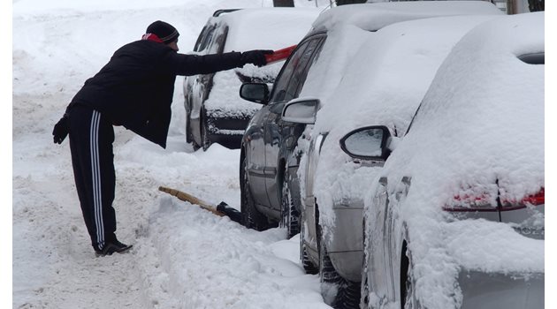 Мъж разчиства колата си, затрупана от сняг СНИМКА: Архив