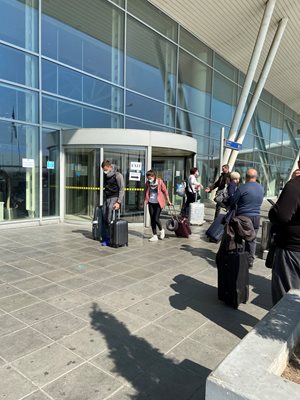 Пристигнали пътници излизат от летището в София. През тази въртяща врата само се излиза, не може да се влезе.