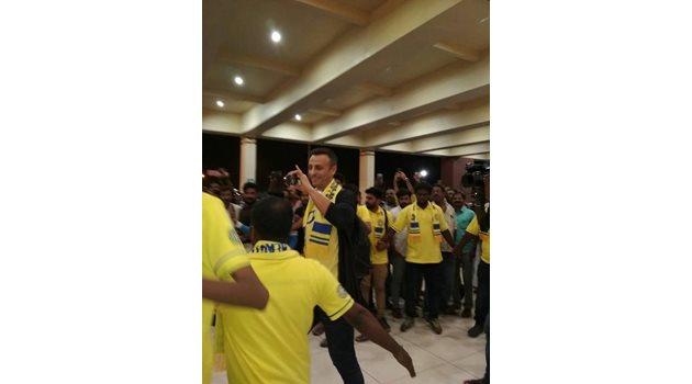 Димитър Бербатов крачи сред "жълтото море" на летището в Индия, облечен с жълта тениска на "Керала" и закичен шалче на клуба.