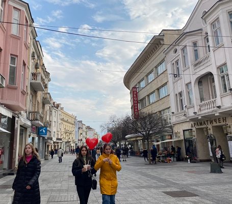 Девойчета вървят по главната улица с балони.