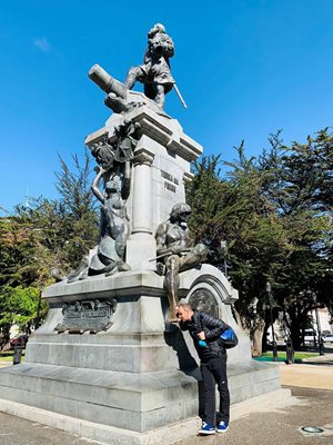 Петър Стойчев до паметника на Фернандо Магелан в Пунта Аренас. Българският плувец спазва традицията за късмет - целува крака на местния индианец, който е увековечен на паметника.