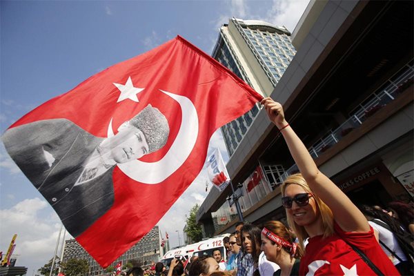 Демонстрант развява турското знаме с лика на Кемал Ататюрк на площад “Таксим” в Истанбул.