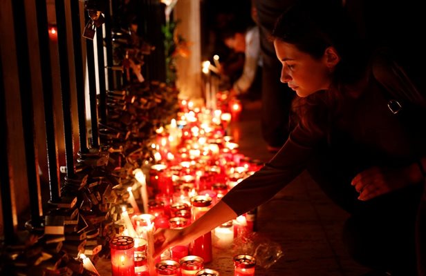 Жена поставя свещ в памет на журналистката на Паметника на любовта.