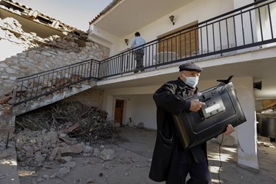 A man rescues a television from dilapidated buildings in Greece.  PHOTO: Reuters