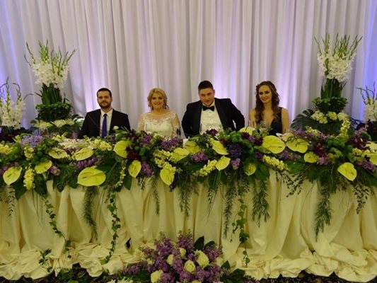 Ева, Стефан и кумовете им на сватбената маса, отрупана с лилави и бели цветя.