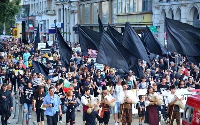 Стотици близки на хора с увреждания излязоха на протест в понеделник вечер в столицата, облечени във фланелки “Системата ни убива” и веещи черни знамена.