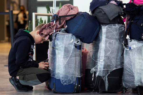 Младеж с куфари чака на летище преди полет