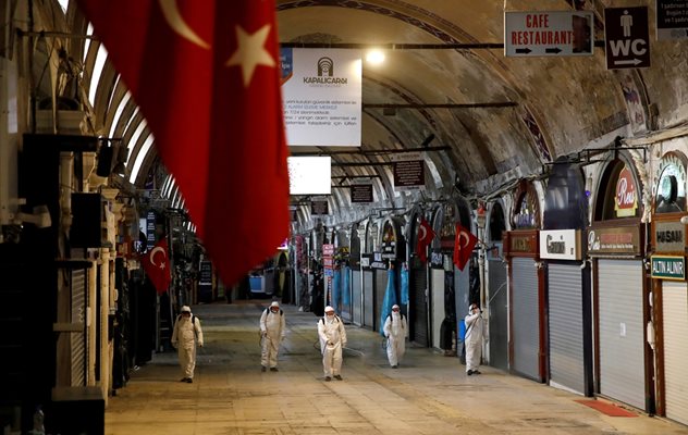 Хора в защитни костюми дезинфекцират закрития пазар в Истанбул.