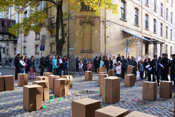 Участници в игрите стоят пред кашони, които представляват макети на сгради. Те бяха закупувани виртуално. Снимка: "Пловдив 2019"