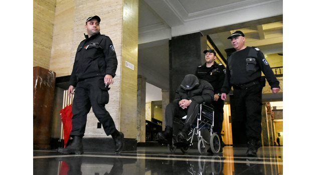 Съдебни охранители водят Герман Костин в инвалидна количка в съда.