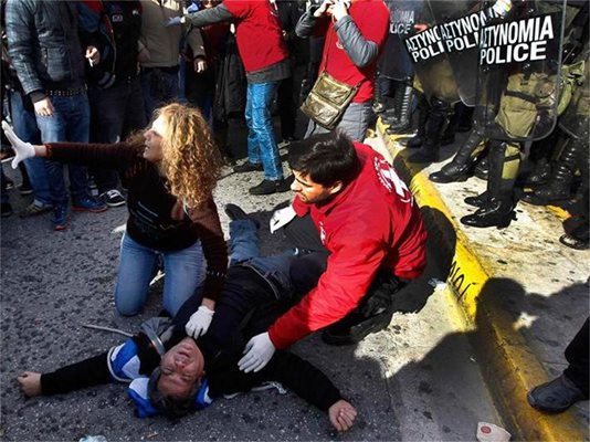 Демонстранти помагат на ранен младеж при сблъсъците с полицията в центъра на Атина. 
СНИМКИ: РОЙТЕРС