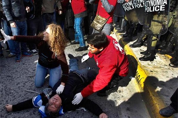 Демонстранти помагат на ранен младеж при сблъсъците с полицията в центъра на Атина. 
СНИМКИ: РОЙТЕРС