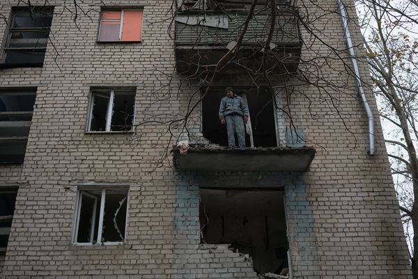 Мъж стои на балкона на апартамента си, който е бил разрушен от руски обстрел в Херсон СНИМКА: Ройтерс