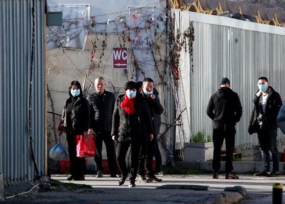 Група китайци с маски наблюдава полицаите.