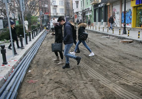 Младежи преминават по разкопаната улица.