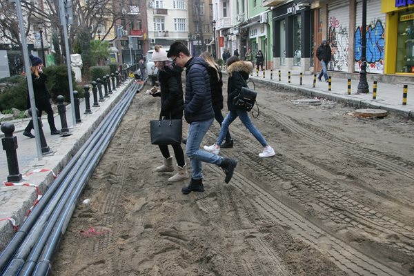 Младежи преминават по разкопаната улица.