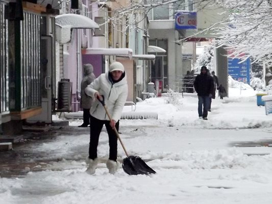 Жена разрива снега от тротоарите в Силистра.
