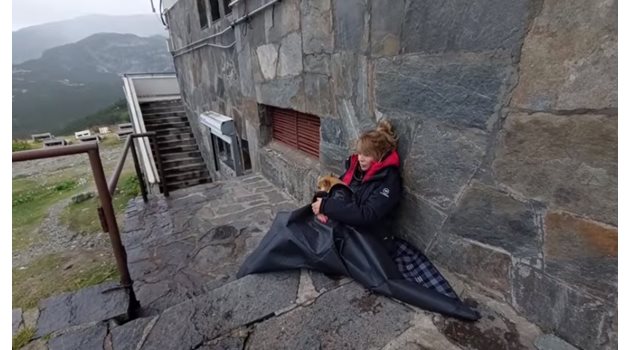 Кадър от видеото, което Мира Добрева споделя в профила си във фейсбук. На него се вижда как журналистката седи отвън пред хижата, прегърнала малкото си кученце.