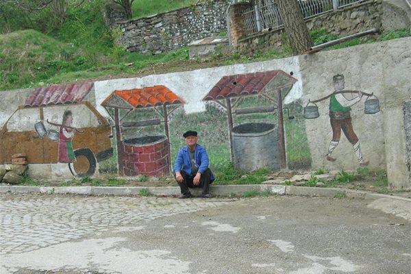 Самоукият художник Йордан Калагларски пред негова творба на улица в селото.