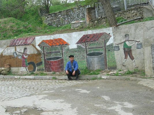 Самоукият художник Йордан Калагларски пред негова творба на улица в селото.