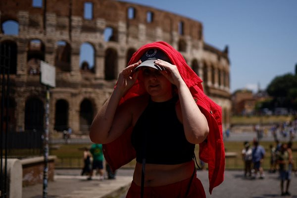 Жена се е покрила с риза, за да се предпази от силното слънце близо до Колизеума. СНИМКА: РОЙТЕРС