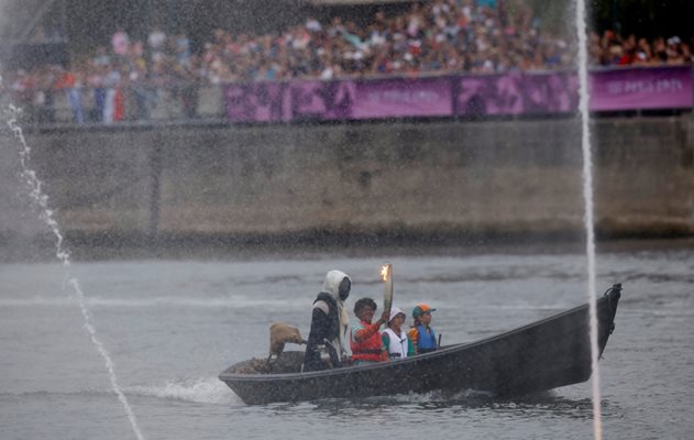 Torchbearers are seen with the Olympic flame in the Seine River Photo: Reuters