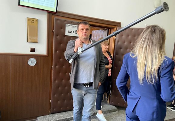 Иво Даскалов се брани от снимащите устройства на репортерите пред съдебната зала.