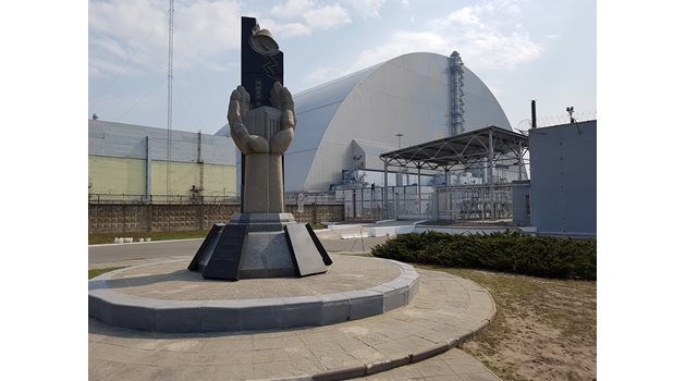 Паметникът на жертвите, загинали заради “Чернобил”. Вдясно е четвърти реактор, покрит със саркофаг.