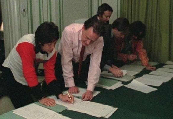 Пол Маккартни подписва споразумението за прекратяване на партьорството. В дъното се вижда и Джордж Харисън.