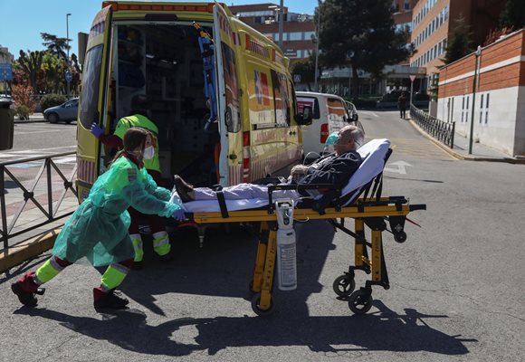 Лекар в защитен костюм вози болен към болница в Мадрид.