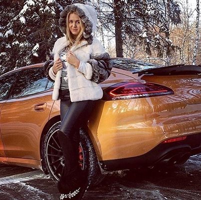 Жена на име Арина позира до златисто Porsche