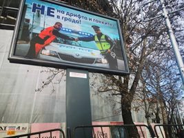 На този билборд пътен полицай и автомобилен състезател си подават ръка