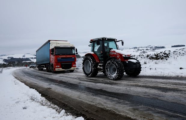 Трактор дърпа закъсал тир в снеговете в Централна Англия.