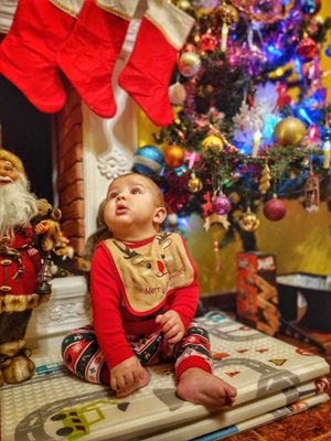 Шестмесечният Кристиан от София получи много подаръци от Дядо Коледа. Понеже му е за първи път, той гледа към комина с надежда, че добрият старец ще се спусне пак и ще му донесе още.