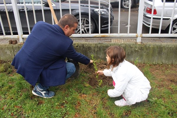 Кметът показва на хлапе как се засажда декоративен храст.