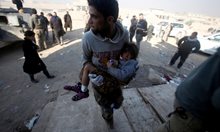 Мъж извежда ранено дете от битката за Мосул