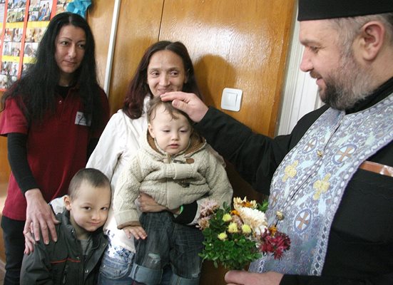 Свещеник поръсва децата на Нина Тодорова, момченцето й не иска да говори. Снимки: Евгени Цветков