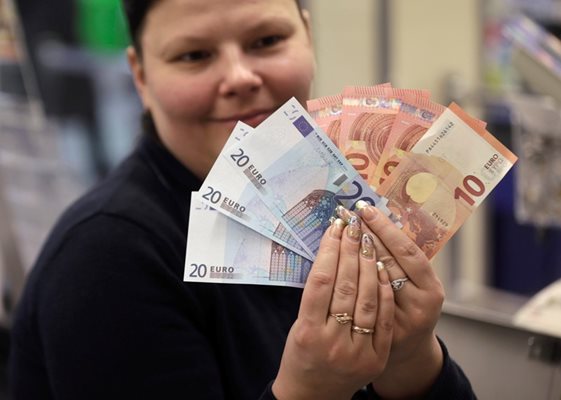 Касиерка в магазин показва евробанкнотите, с които вече тече търговията в прибалтийската страна.