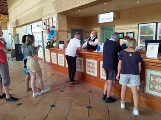 Служител на рецепцията с маска дава напътствия на гостите на блокирания хотел в Тенерифе.
