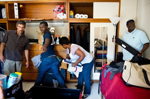 Родители помагат на сина си да подреди багажа си в стая на общежитието на университета